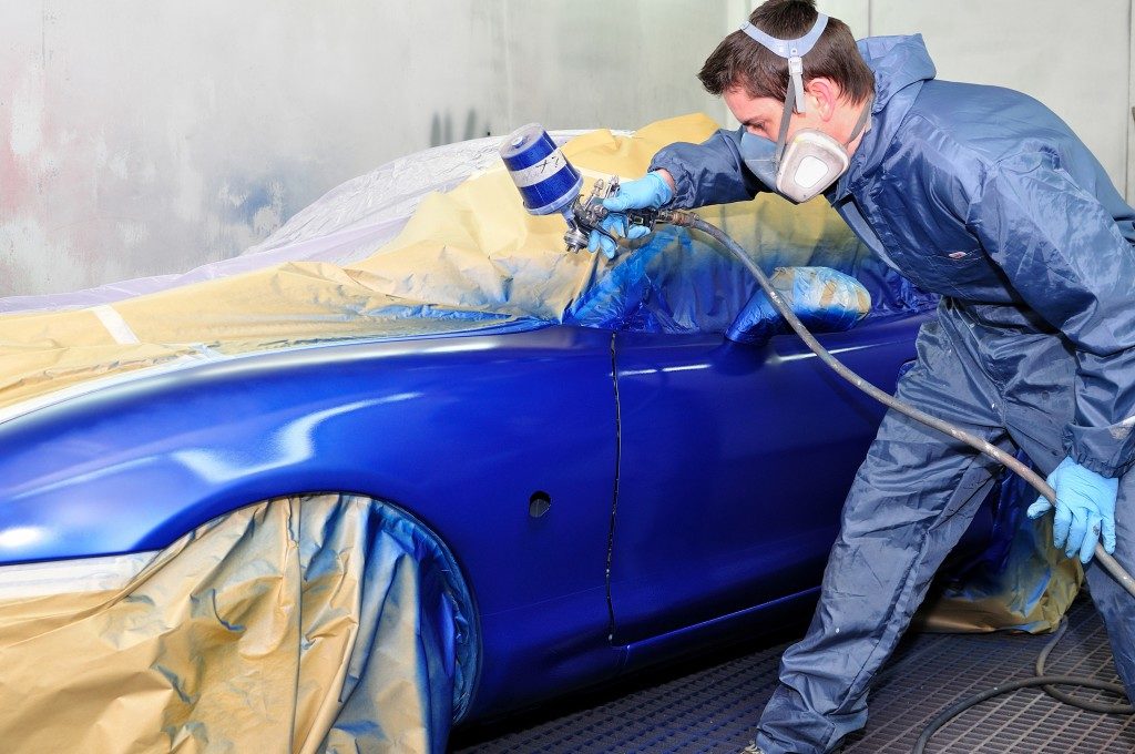 Worker painting a car in paint booth