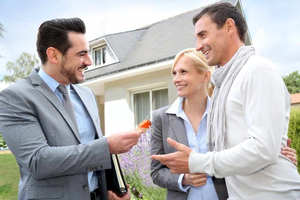 Real estate agent giving home keys to property owners