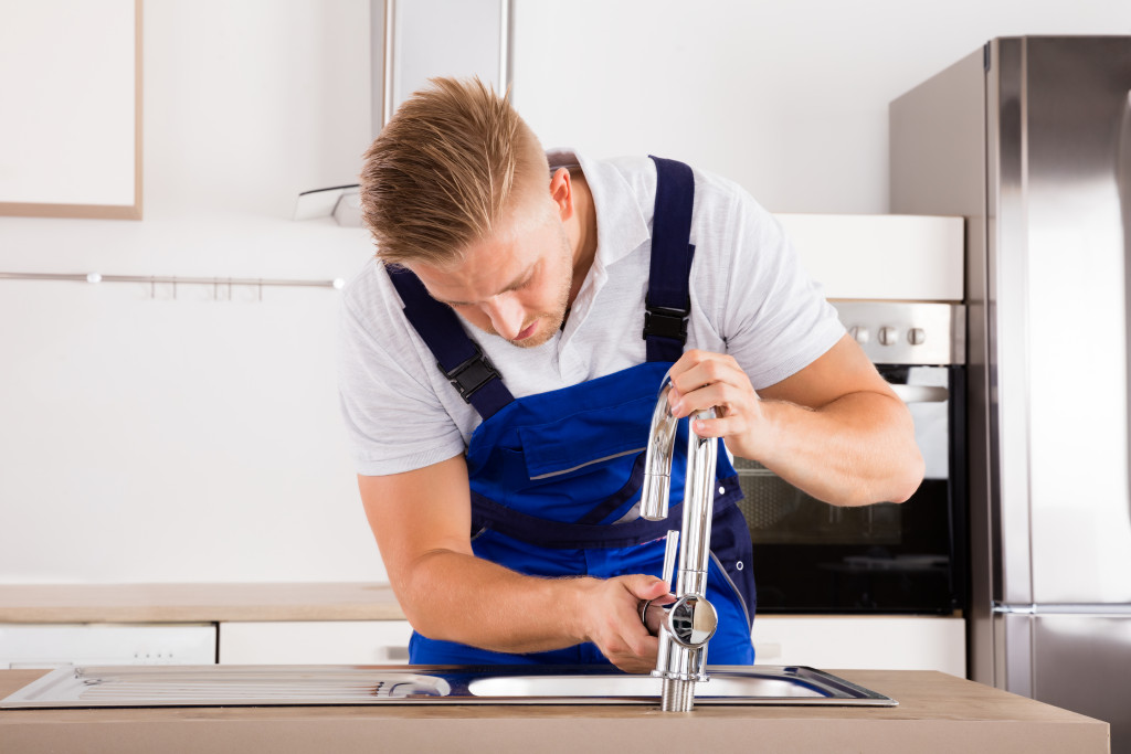a white guy installing a new faucet in a well-lit kitchen
