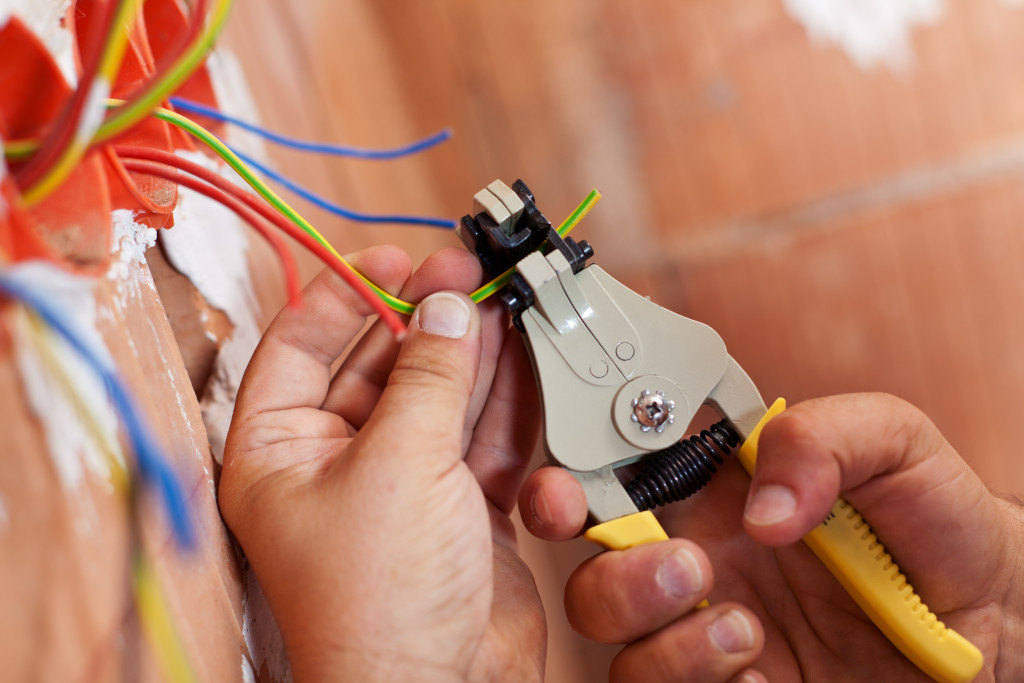 An electrician peeling off insulation from wires using a wire stripper