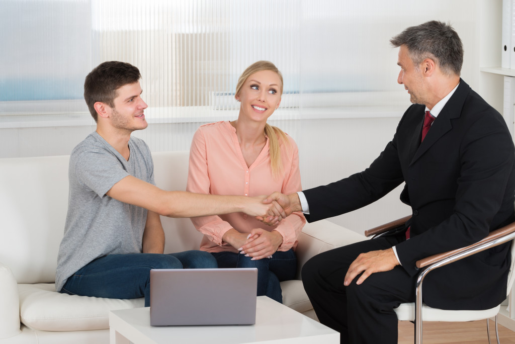 a man shaking hands with a professional agent while a woman watches